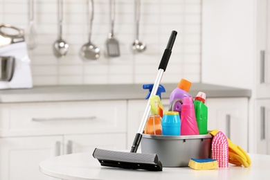 Set of cleaning supplies on table in kitchen. Space for text