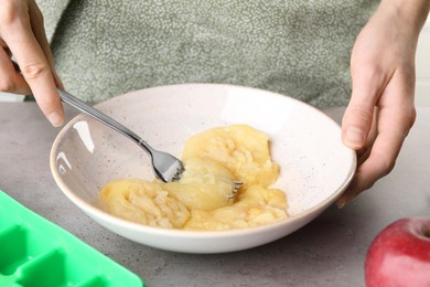 Photo of Woman making apple puree for freezing in cube tray, closeup