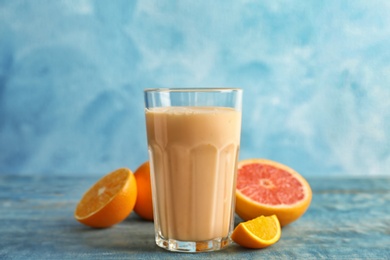 Photo of Glass with healthy detox smoothie and citrus fruits on table