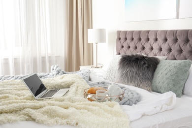 Photo of Tray with tasty breakfast and laptop on bed