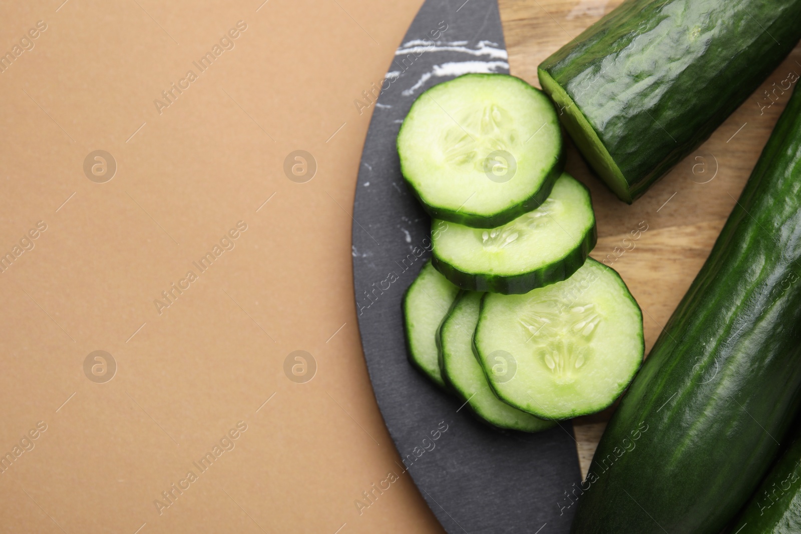 Photo of Fresh cucumbers on beige background, top view. Space for text