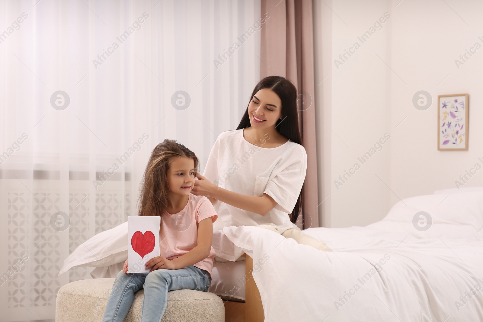 Photo of Happy woman and her daughter spending time together on bed at home, space for text. Mother's day celebration