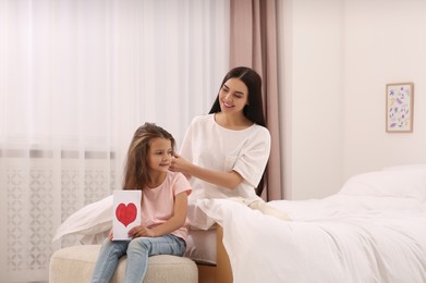 Photo of Happy woman and her daughter spending time together on bed at home, space for text. Mother's day celebration