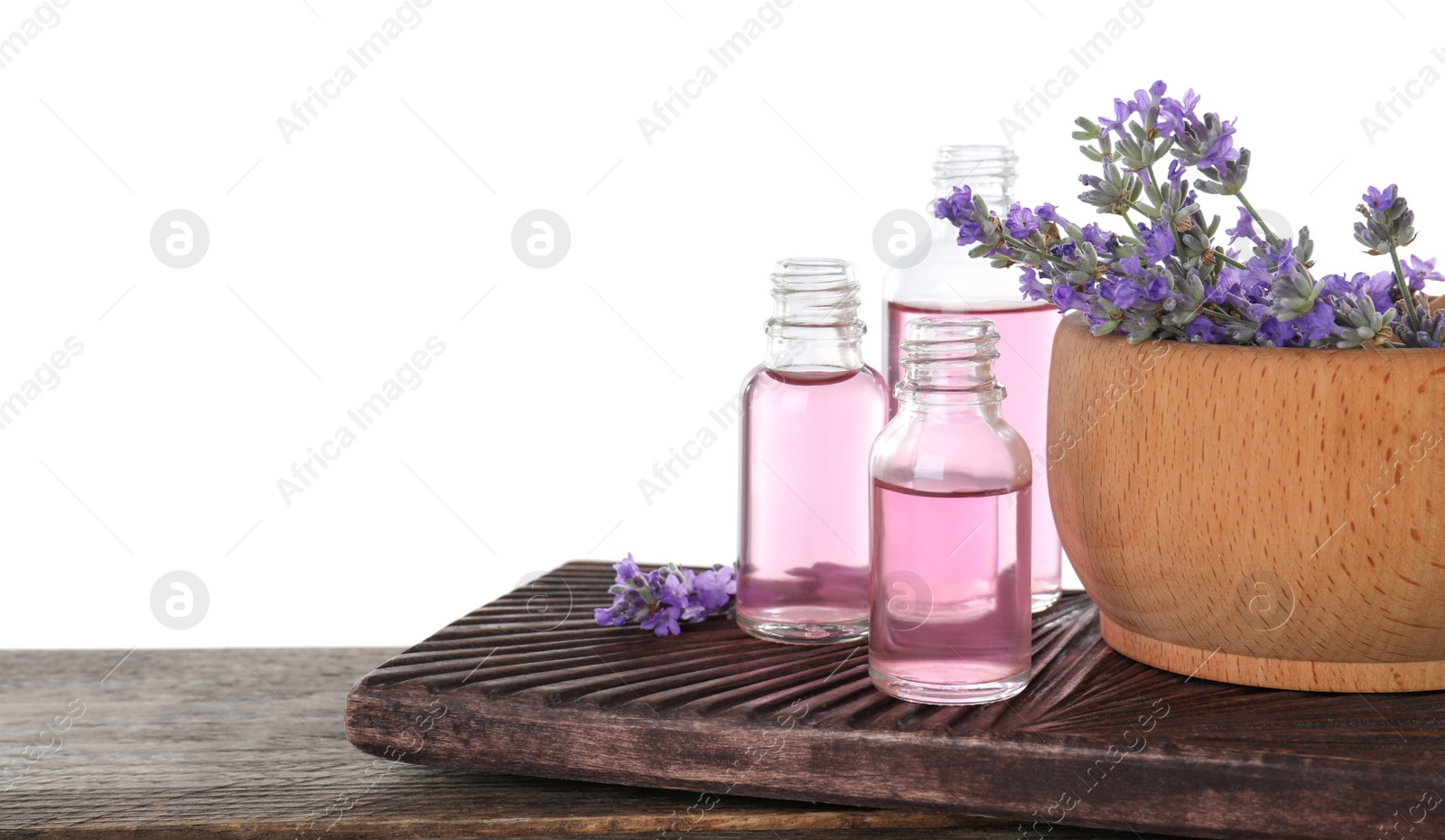 Photo of Bottles of lavender essential oil and bowl with lavender flowers on wooden table against white background