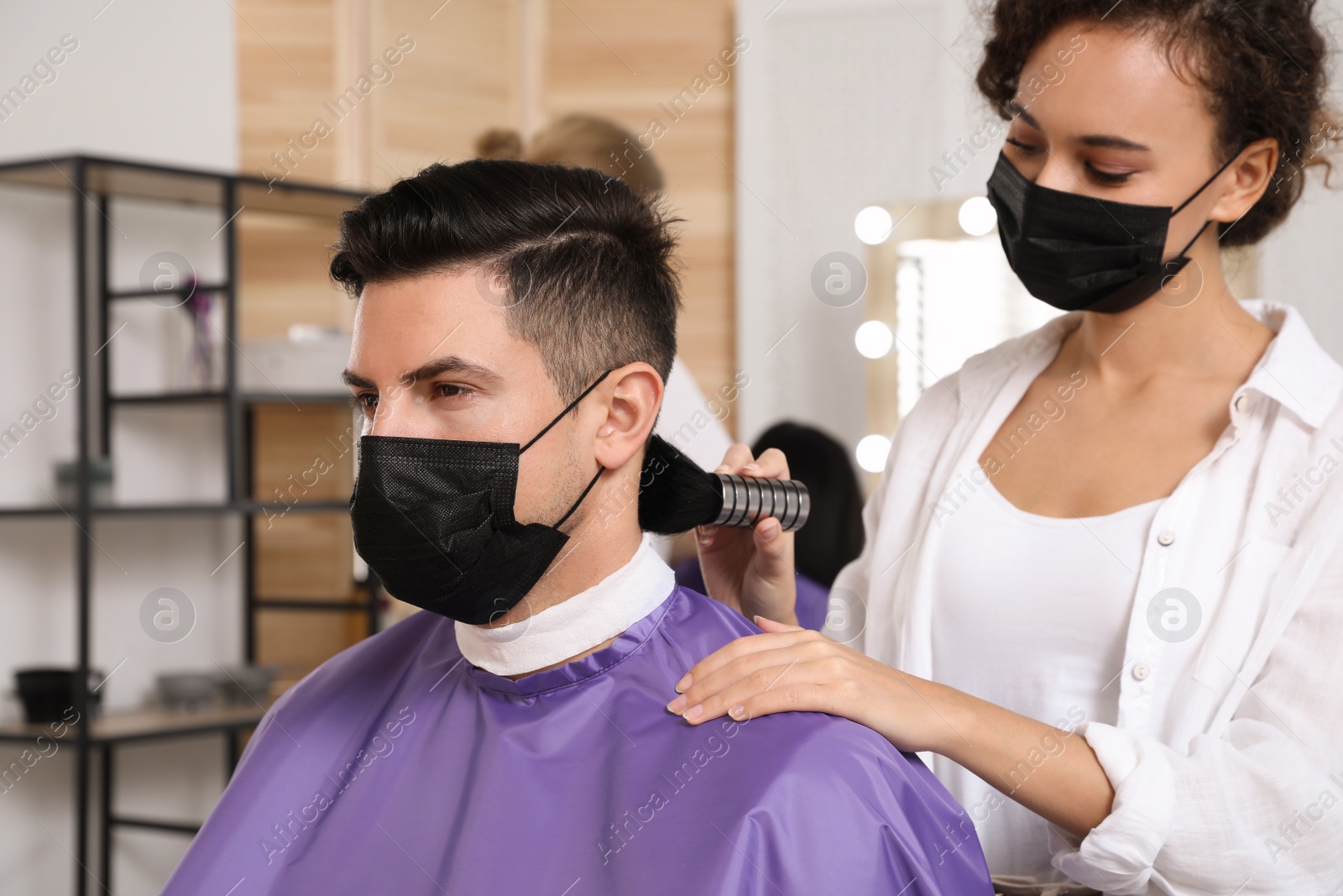 Photo of Professional stylist working with client in salon. Hairdressing services during Coronavirus quarantine