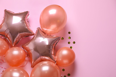 Colorful balloons and confetti on pink background, flat lay. Space for text