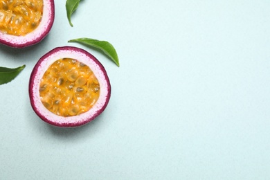 Photo of Halves of fresh ripe passion fruit (maracuya) with leaves on light background, flat lay. Space for text