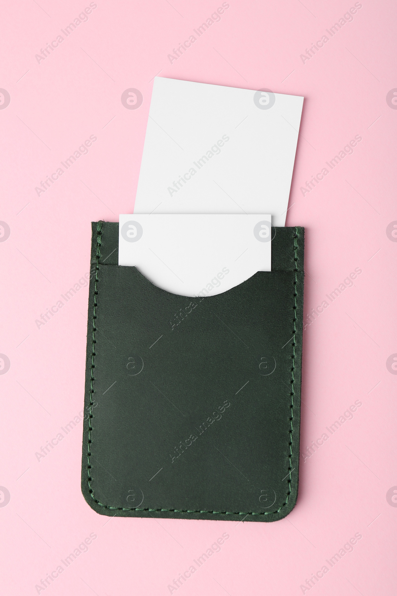 Photo of Leather business card holder with blank cards on pink background, top view