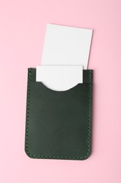 Leather business card holder with blank cards on pink background, top view