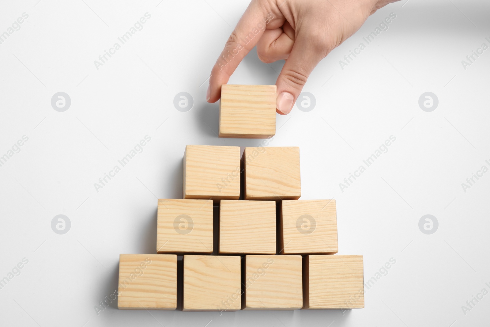 Photo of Closeup view of woman building pyramid with wooden cubes on white background, top view. Career promotion concept
