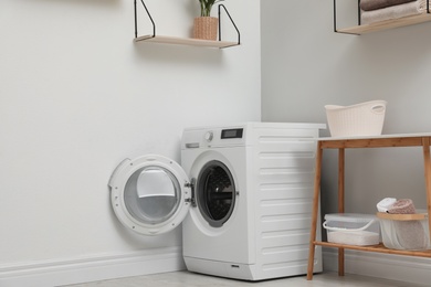 Modern washing machine in laundry room interior