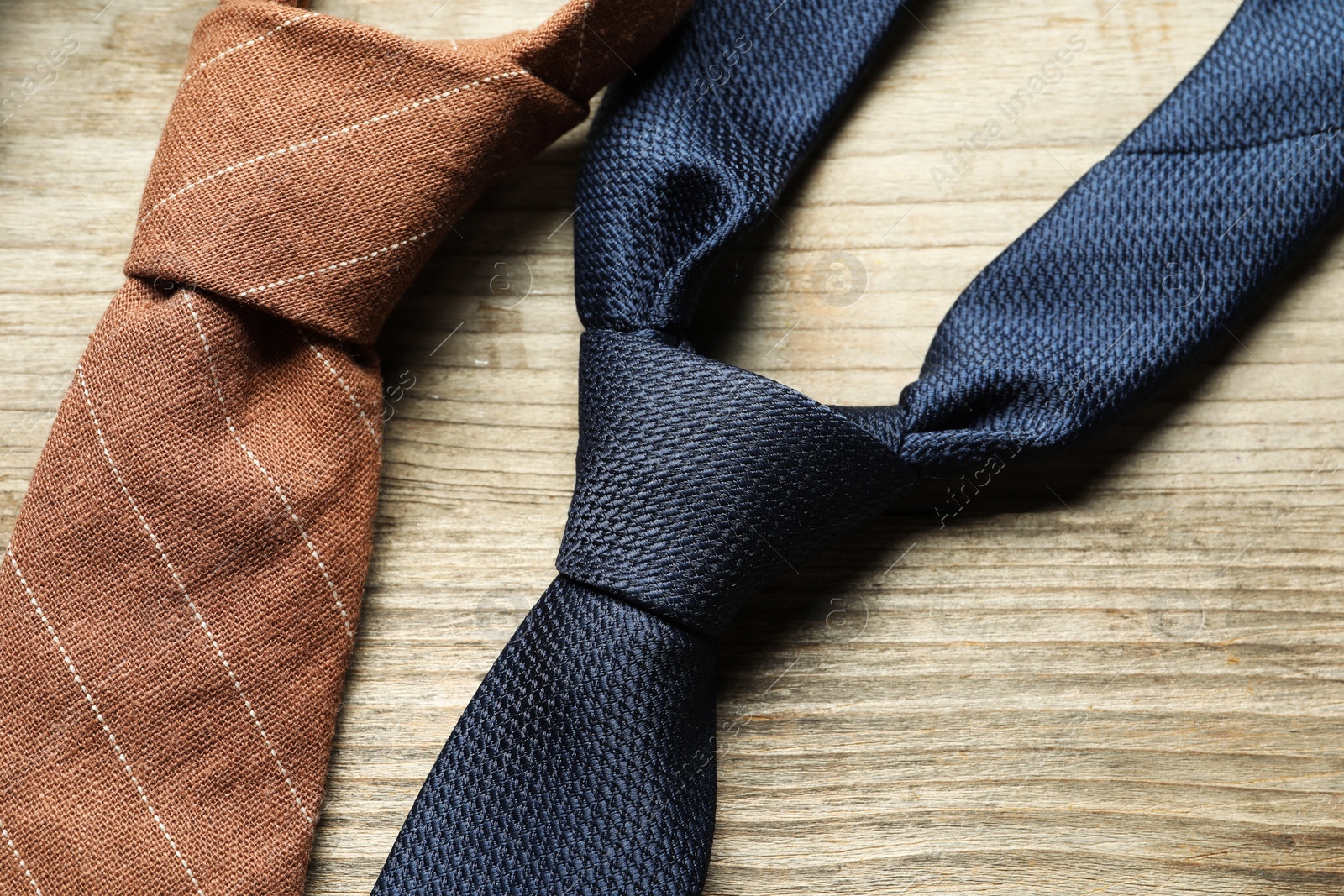 Photo of Two neckties on light wooden table, top view