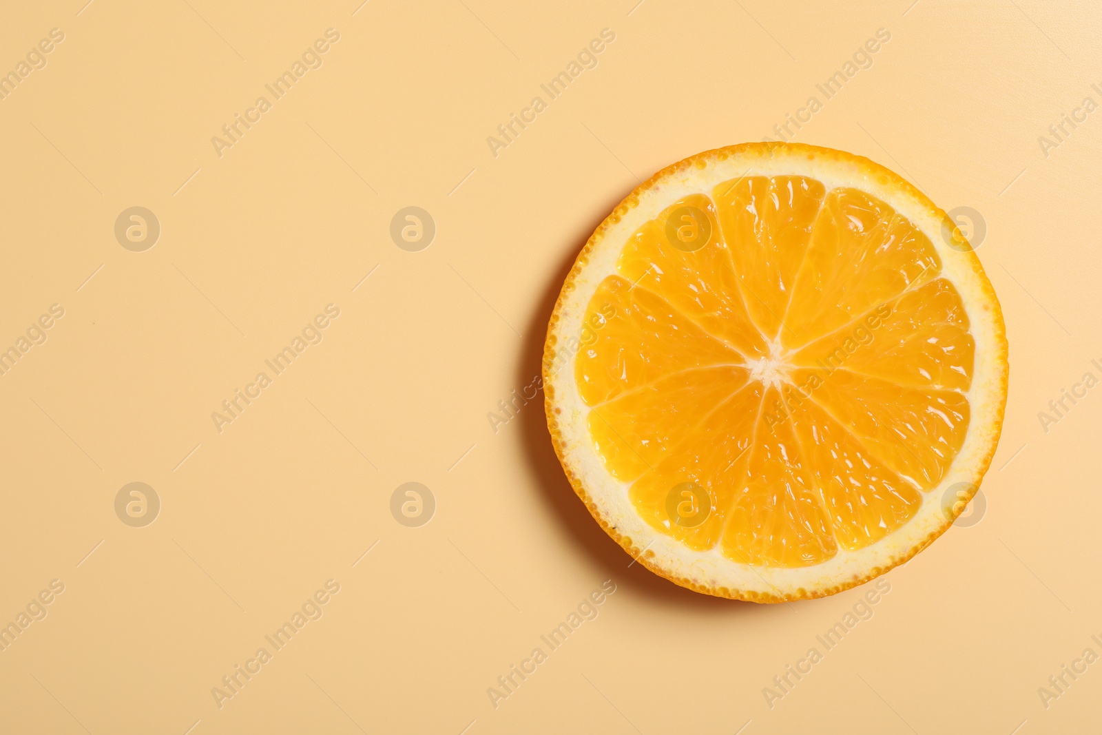 Photo of Slice of juicy orange on beige background, top view. Space for text