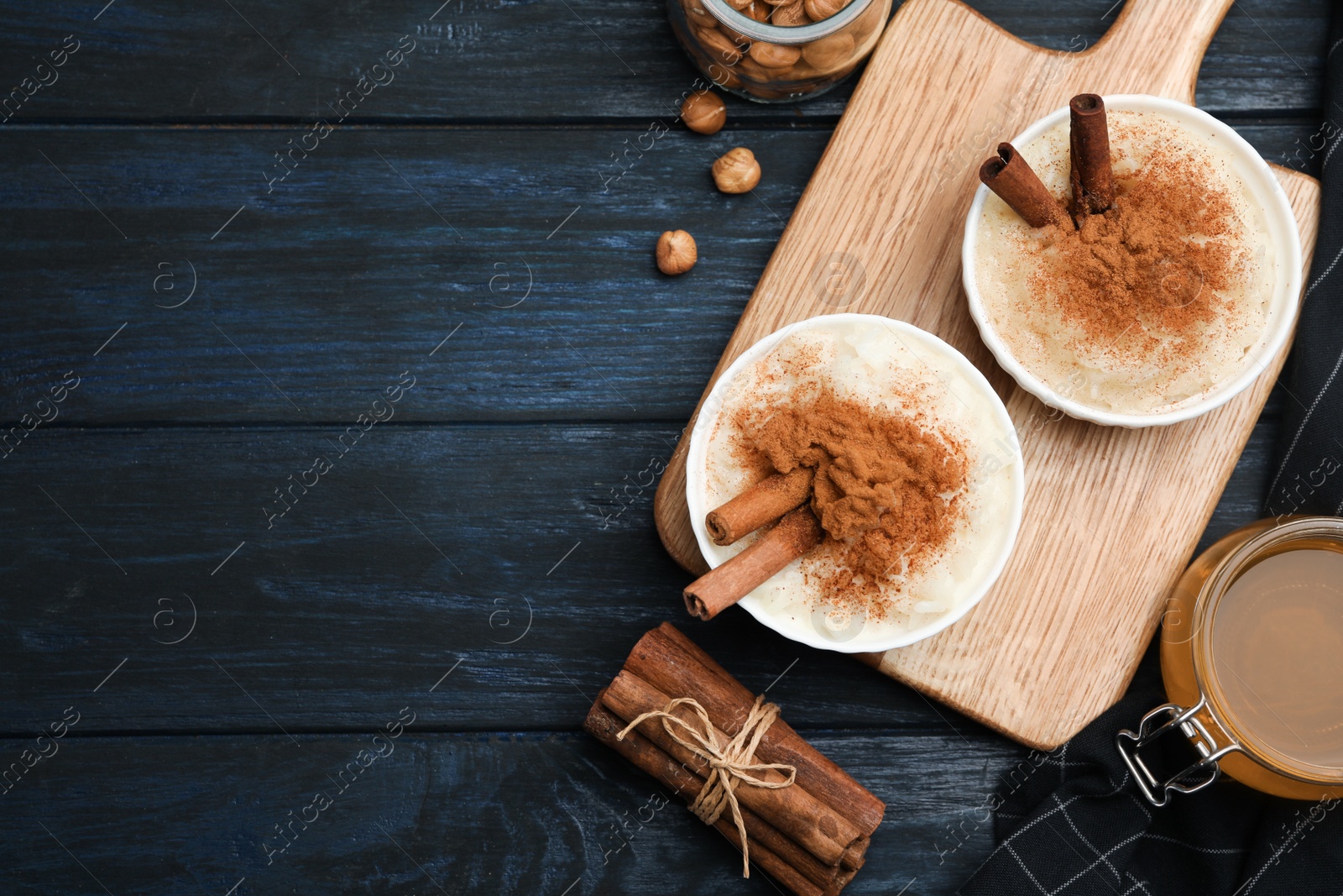 Photo of Delicious rice pudding with cinnamon on dark wooden table, flat lay. Space for text