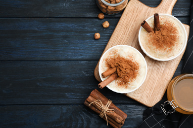 Delicious rice pudding with cinnamon on dark wooden table, flat lay. Space for text