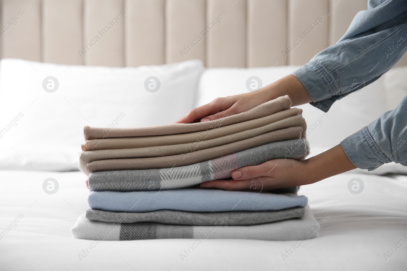 Photo of Woman with folded cashmere clothes on bed, closeup