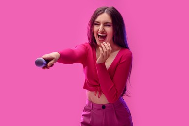 Emotional singer giving microphone to others on pink background