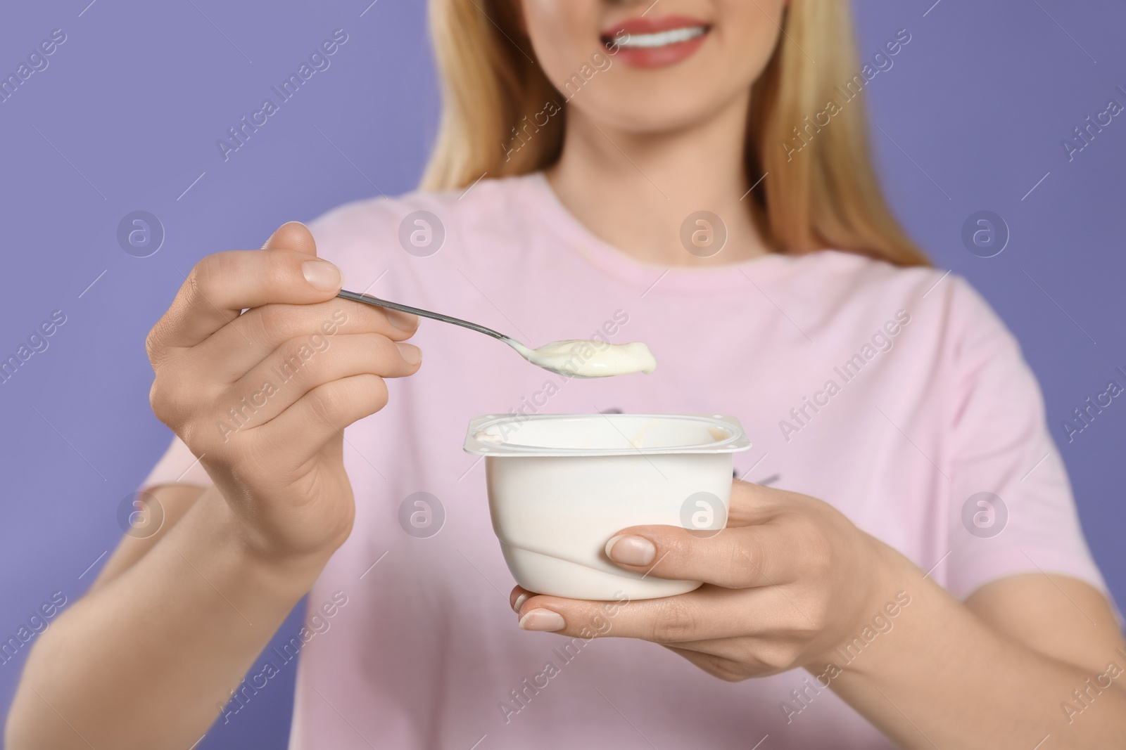 Photo of Closeup of woman with tasty yogurt on violet background