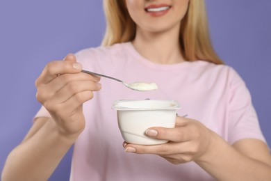 Photo of Closeup of woman with tasty yogurt on violet background