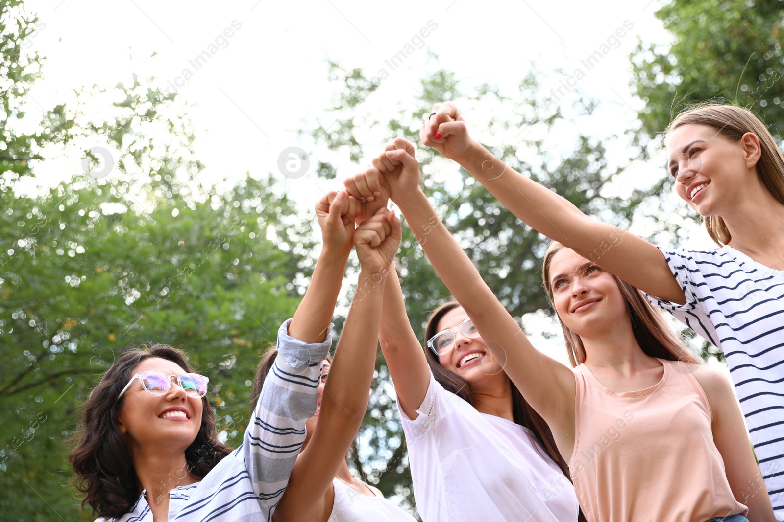 Photo of Happy women raising hands outdoors. Girl power concept