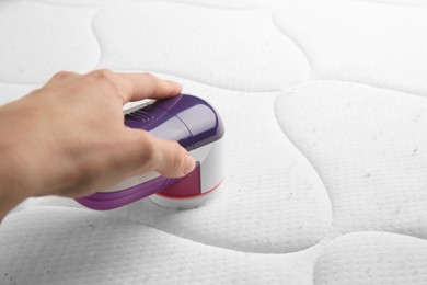 Photo of Woman using fabric shaver on mattress with lint, closeup. Space for text