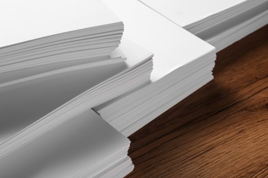 Photo of Stacks of white paper sheets on wooden table, closeup. Space for text