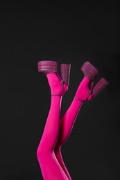 Photo of Woman wearing pink tights and high heeled shoes with platform and square toes on black background, closeup