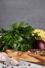 Photo of Bunch of fresh parsley, lemon, onion, garlic and spices on grey textured table