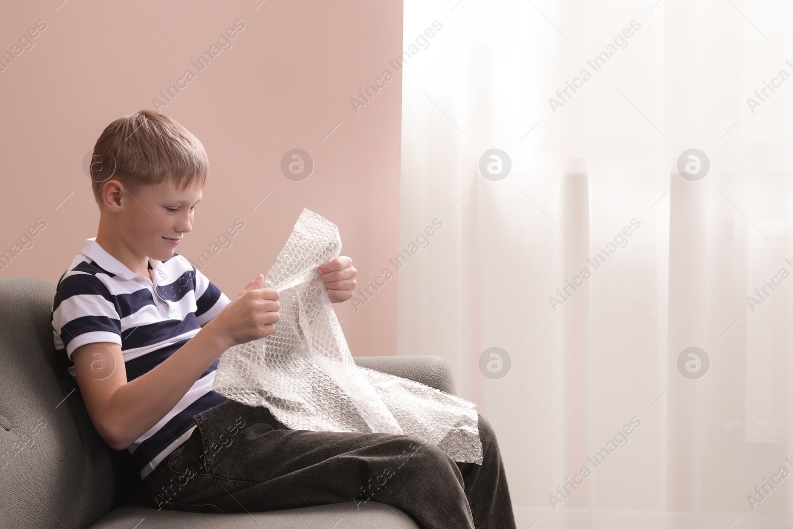 Photo of Boy popping bubble wrap at home, space for text. . Stress relief