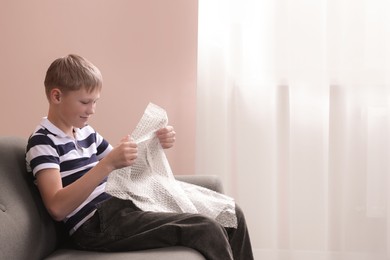 Boy popping bubble wrap at home, space for text. . Stress relief