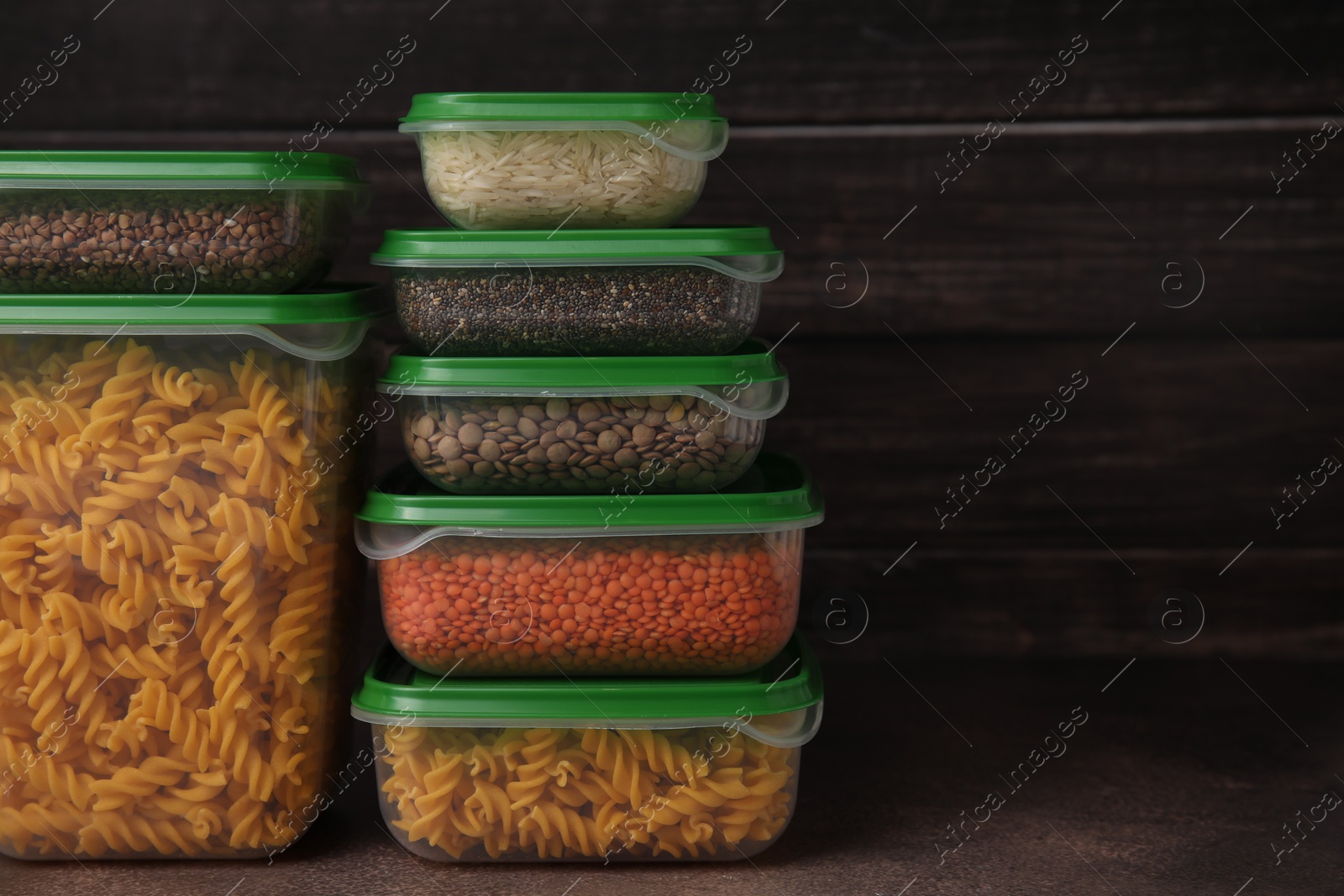 Photo of Plastic containers filled with food products on brown table. Space for text