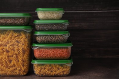 Plastic containers filled with food products on brown table. Space for text