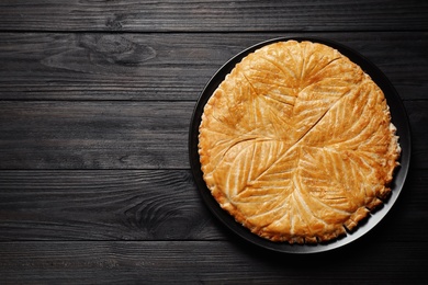 Photo of Traditional galette des rois on black wooden table, top view. Space for text