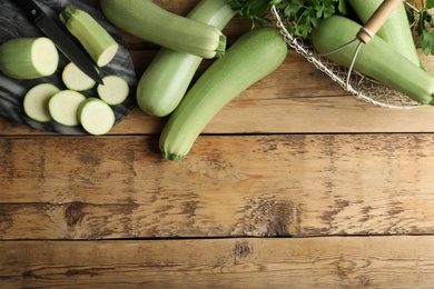Photo of Green ripe zucchinis on wooden table, flat lay. Space for text