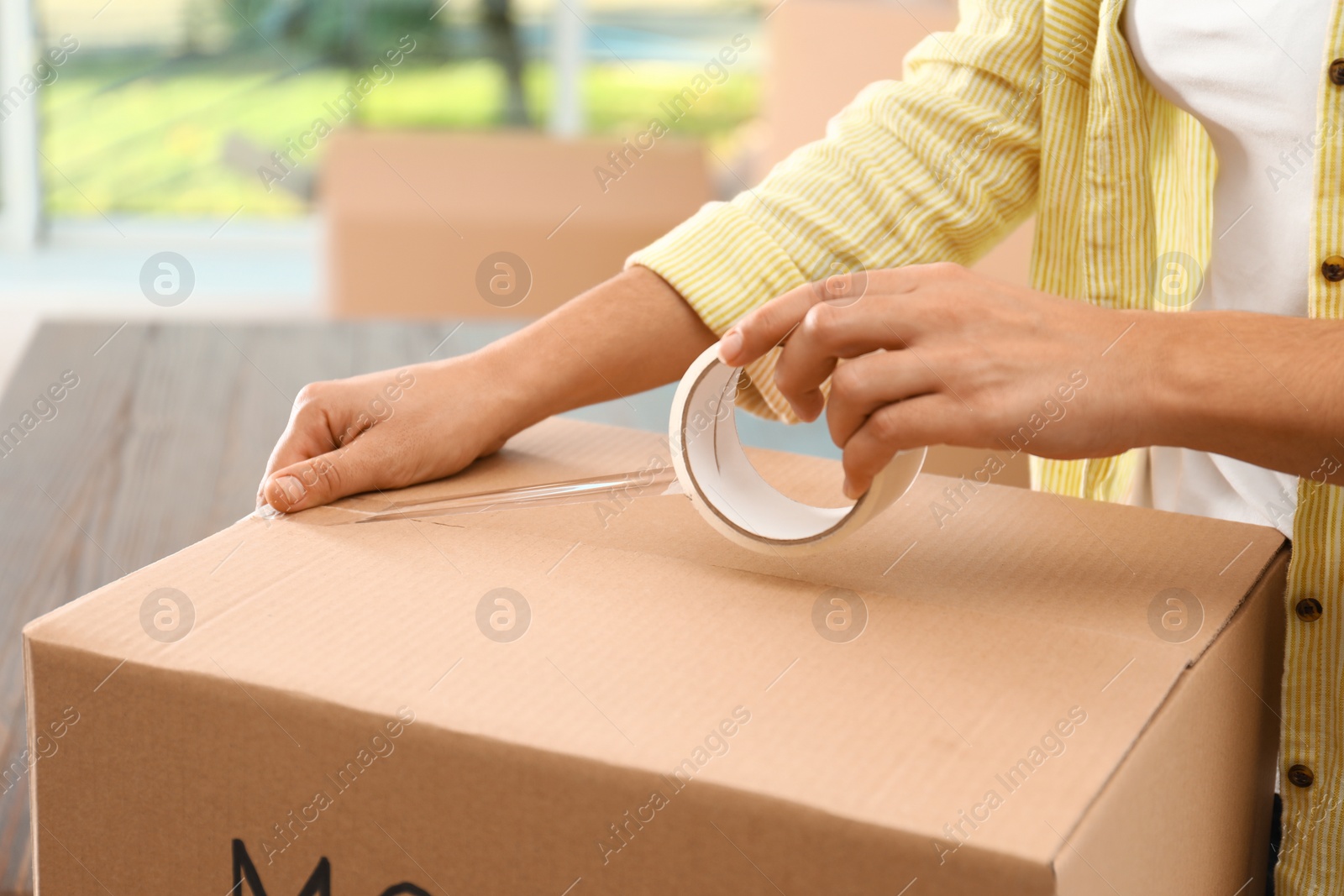 Photo of Woman packing box at table, closeup. Moving day