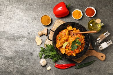 Delicious chicken curry and ingredients on grey table, flat lay. Space for text