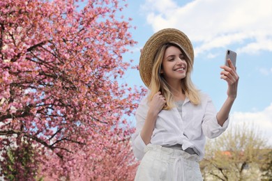 Happy woman taking selfie outdoors on spring day