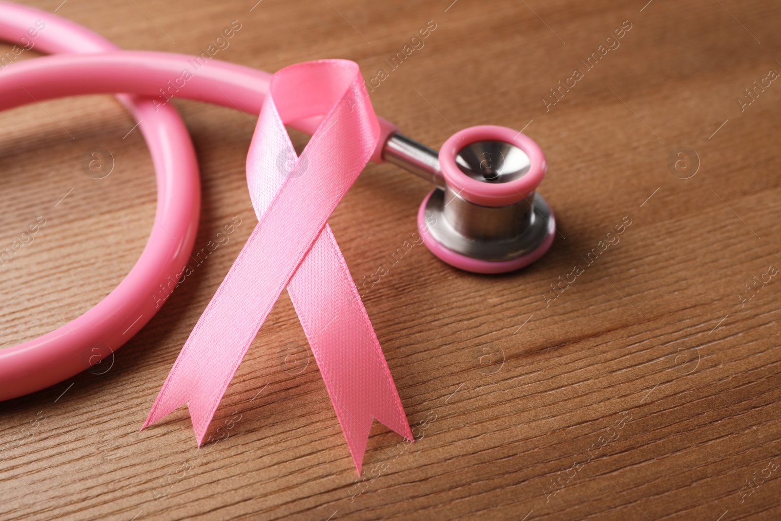 Photo of Pink ribbon and stethoscope on wooden background. Breast cancer concept