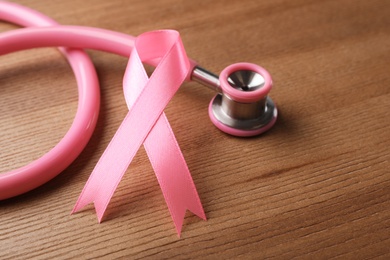 Pink ribbon and stethoscope on wooden background. Breast cancer concept