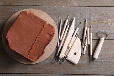 Clay and set of modeling tools on wooden table, flat lay