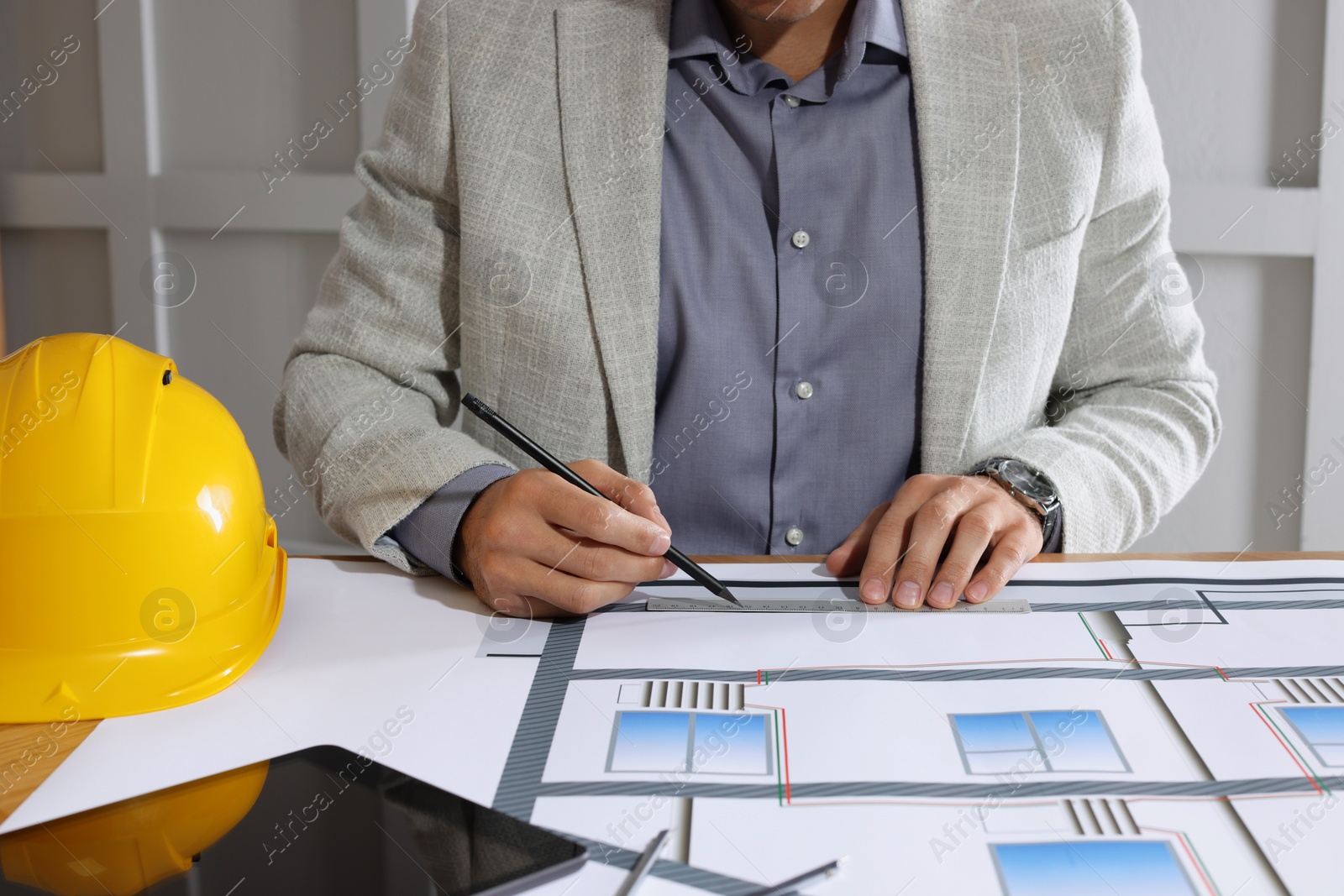 Photo of Architect working with construction drawings indoors, closeup