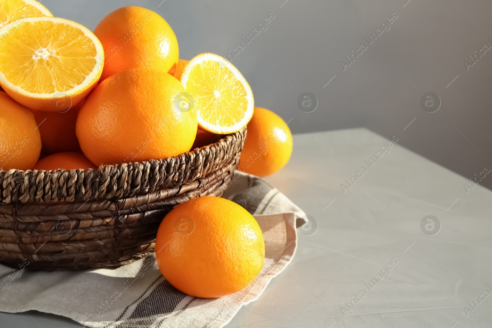 Photo of Fresh juicy oranges in wicker basket on table. Space for text