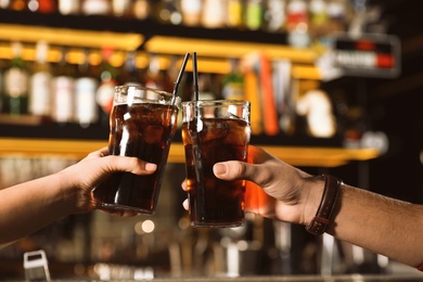 Young couple with glasses of cola in bar, closeup