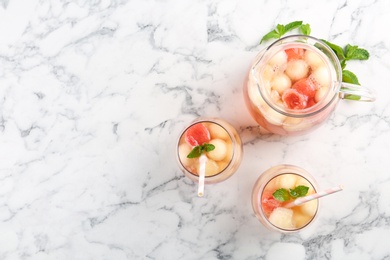Photo of Melon and watermelon ball cocktail with mint served on white marble table, flat lay. Space for text