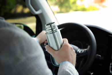 Photo of Man with thermos driving car, closeup view
