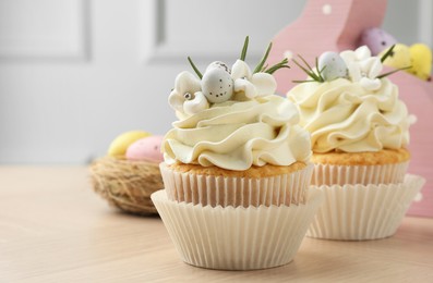 Photo of Tasty Easter cupcakes with vanilla cream on wooden table, space for text