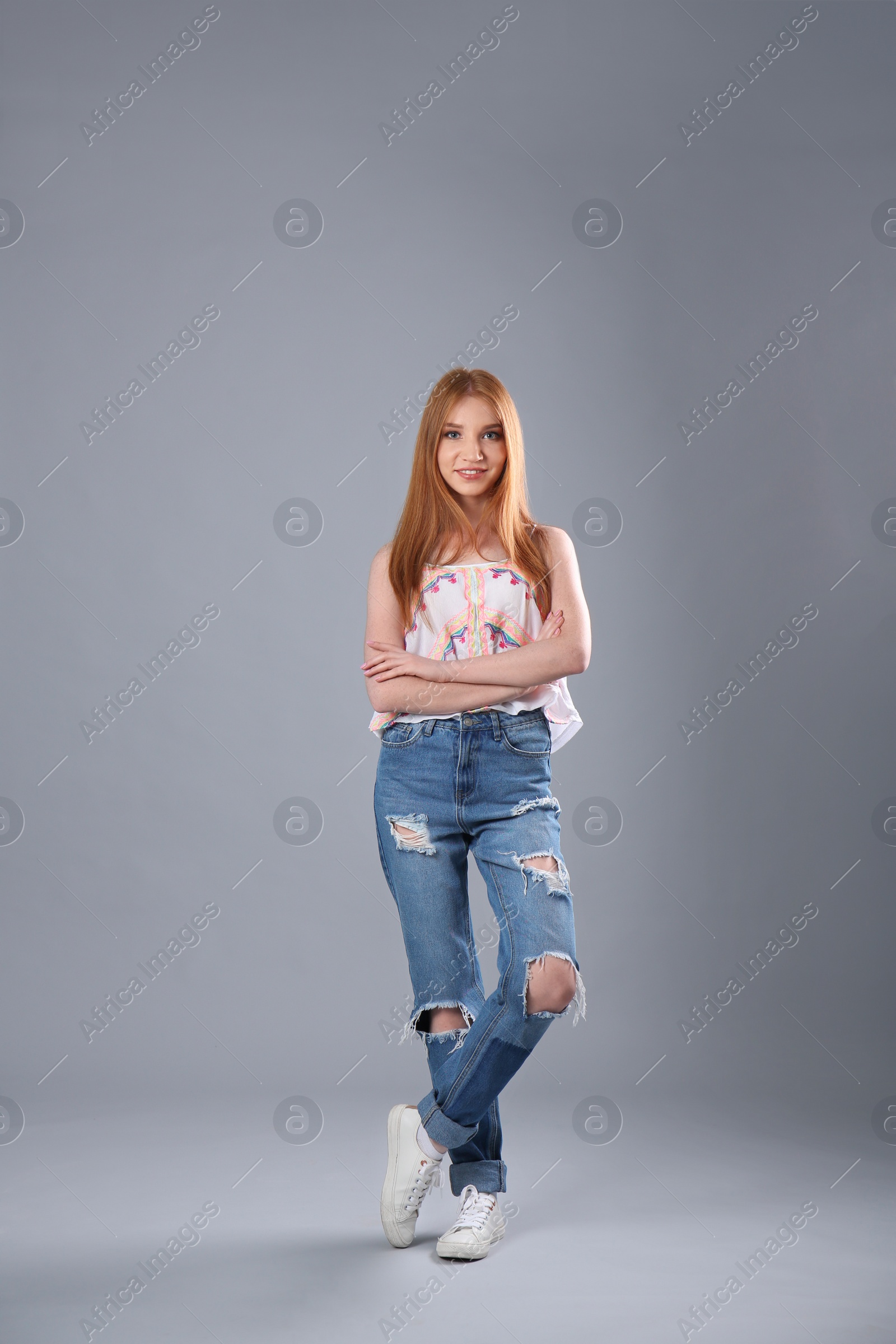 Photo of Young woman in stylish jeans on grey background