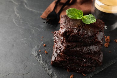 Delicious chocolate brownies with fresh mint on black table. Space for text