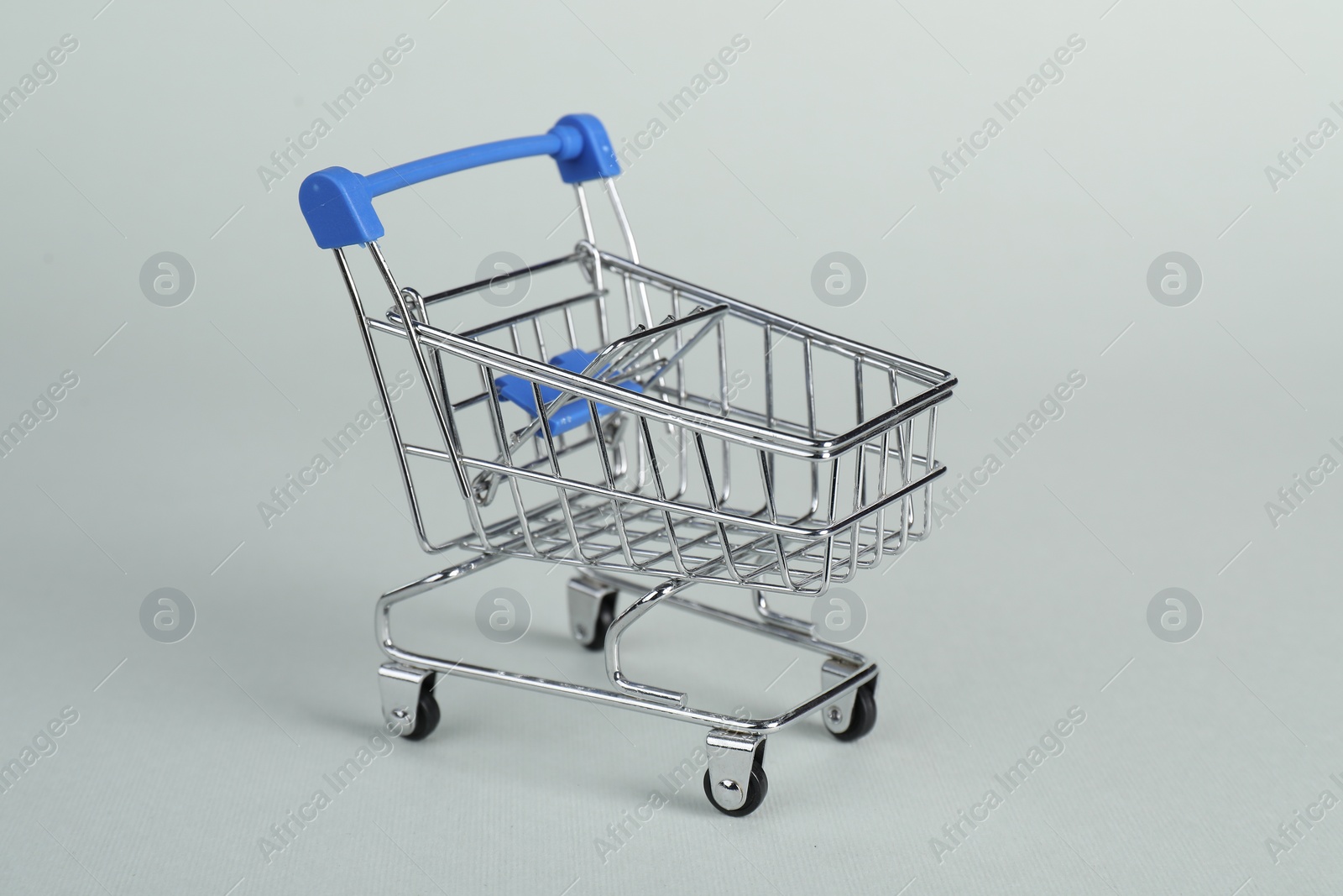 Photo of Small metal shopping cart on light background