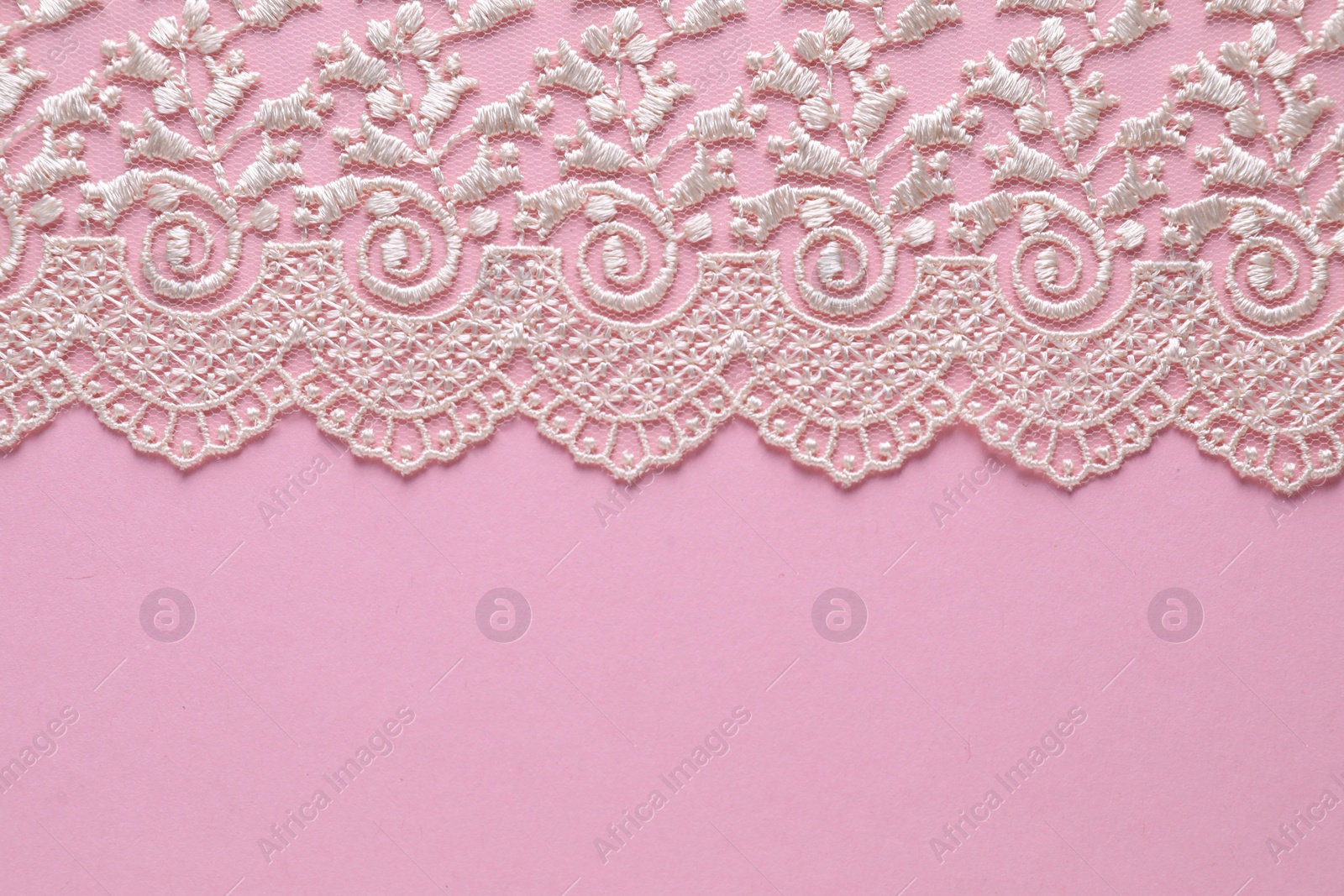 Photo of White lace on pink background, top view. Space for text